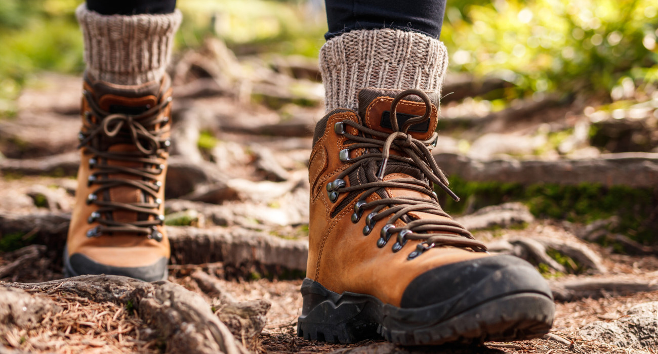 Hiking boot. Legs on mountain trail during trekking in forest. Leather ankle shoes
